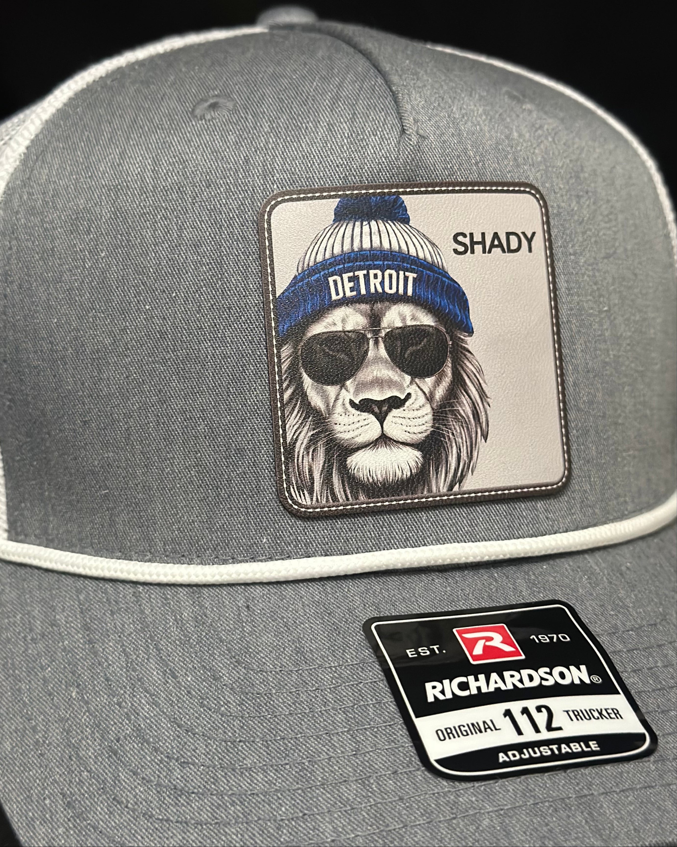Gray trucker hat with a patch of a lion wearing sunglasses and a beanie, with 'Shady' text, and Richardson hat logo.